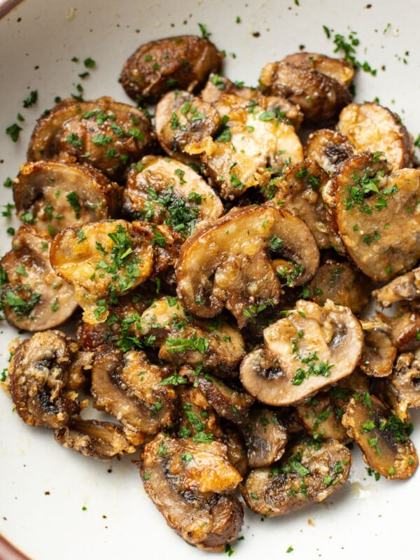 a bowl of sliced air fryer mushrooms topped with parsley