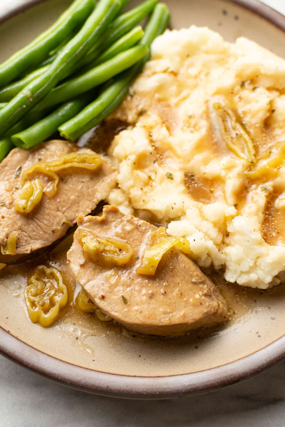 a plate with mississippi pork tenderloin, mashed potatoes, and green beans