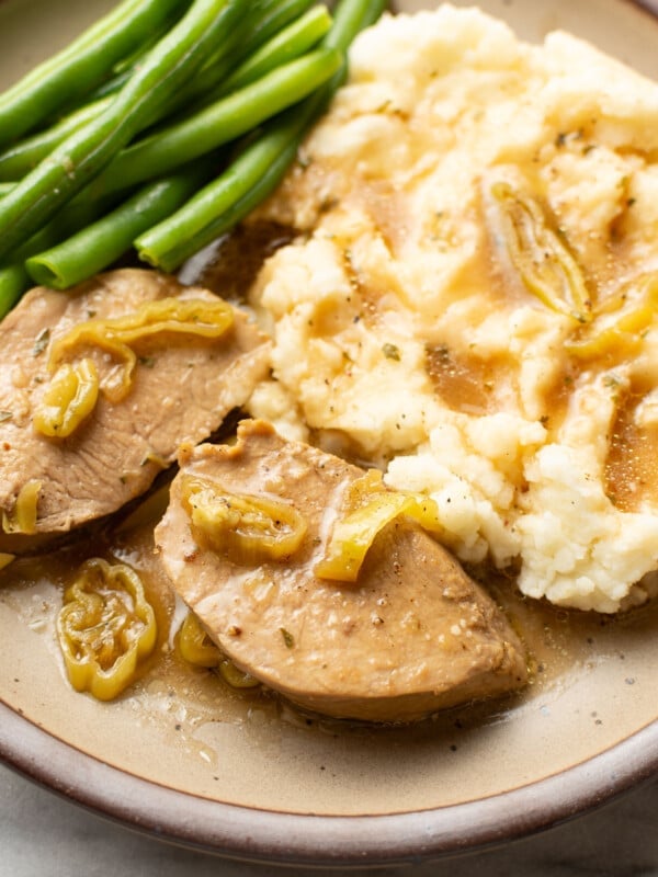 a plate with mississippi pork tenderloin, mashed potatoes, and green beans