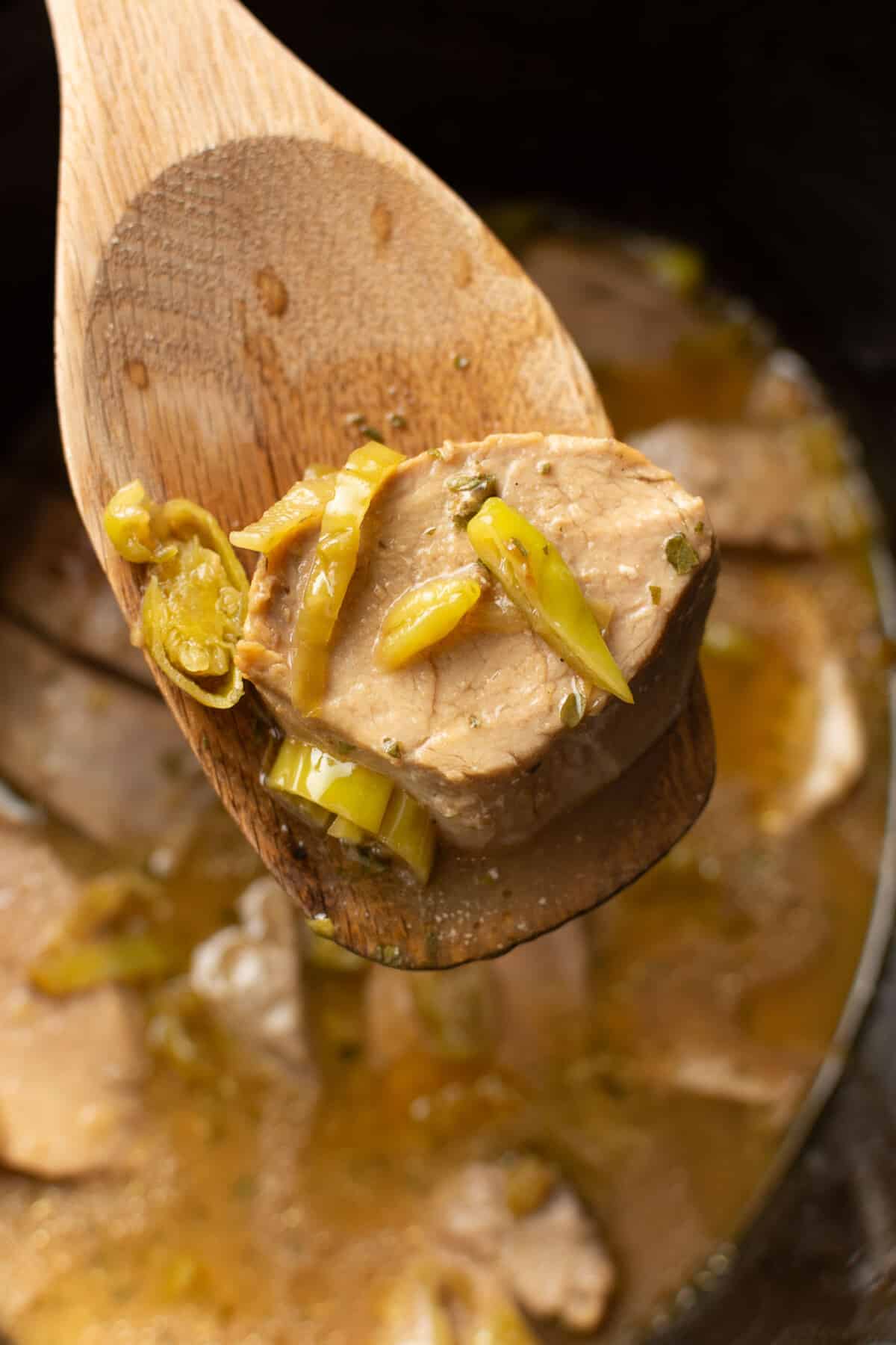 a crockpot with mississippi pork tenderloin and a wooden spoon