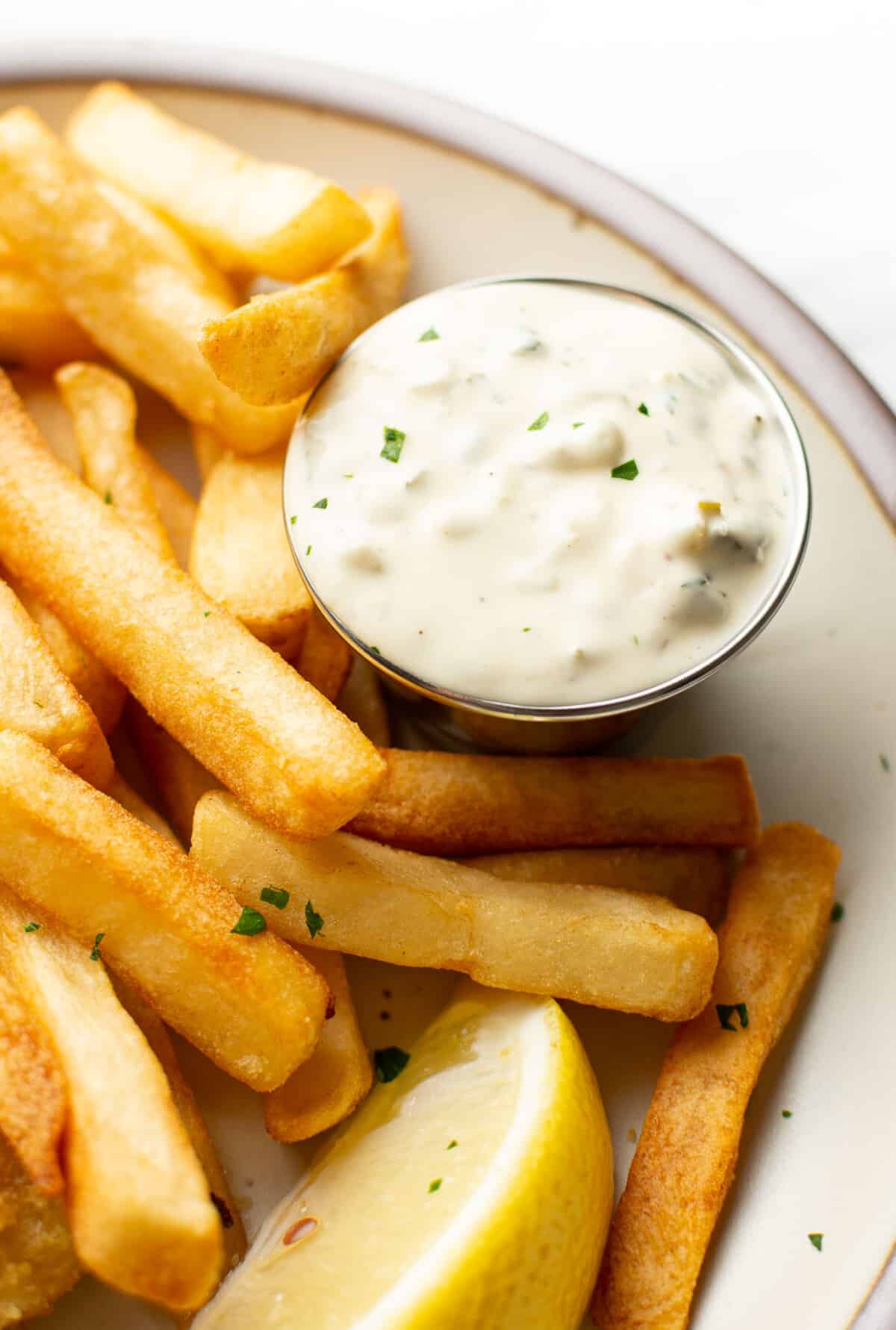 closeup of a plate with fish and chips and homemade tartar sauce