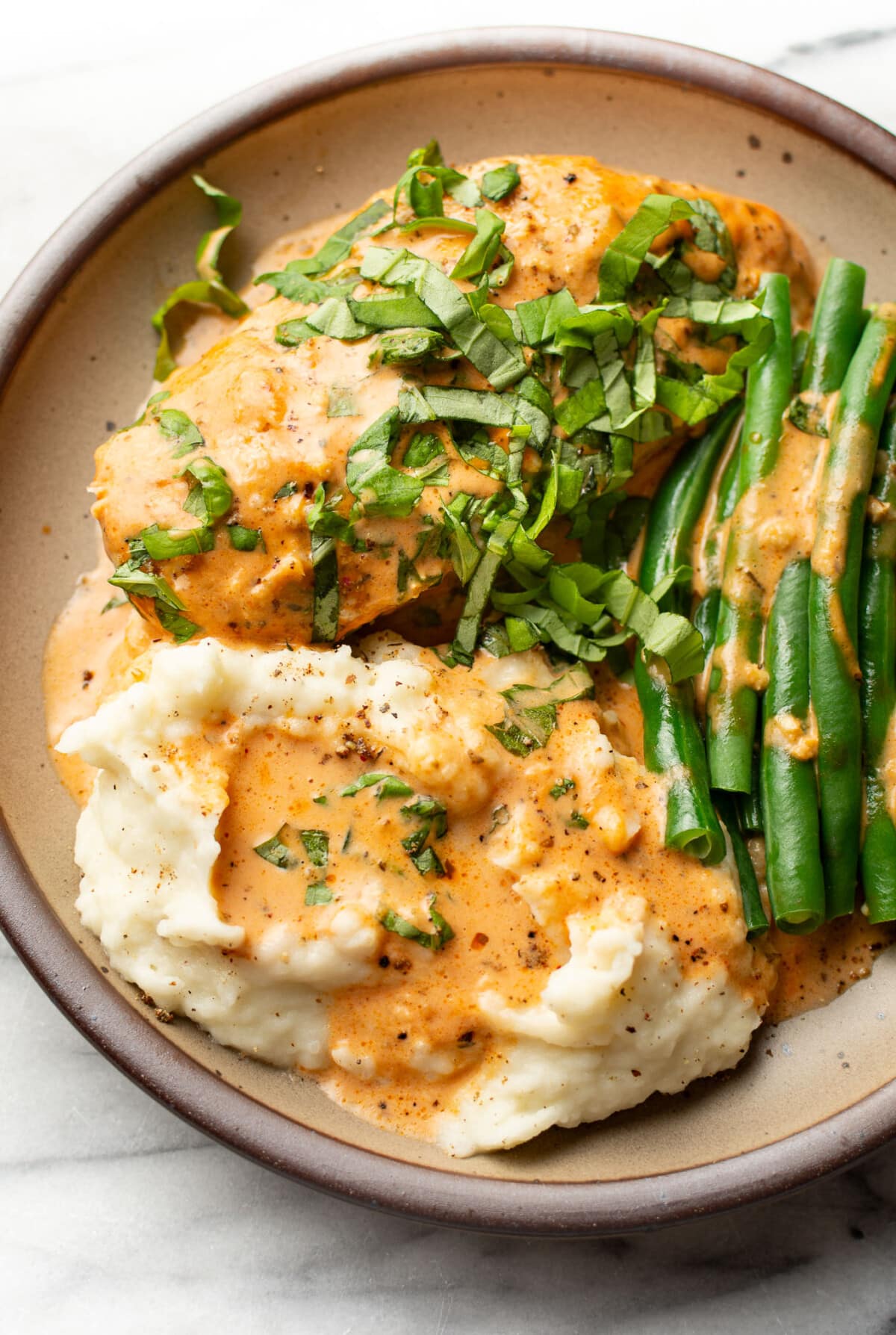 a plate with baked tomato basil chicken, green beans, and mashed potatoes
