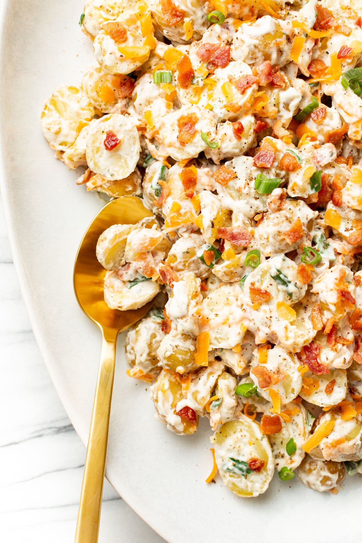 a plate with bacon ranch potato salad and a serving spoon