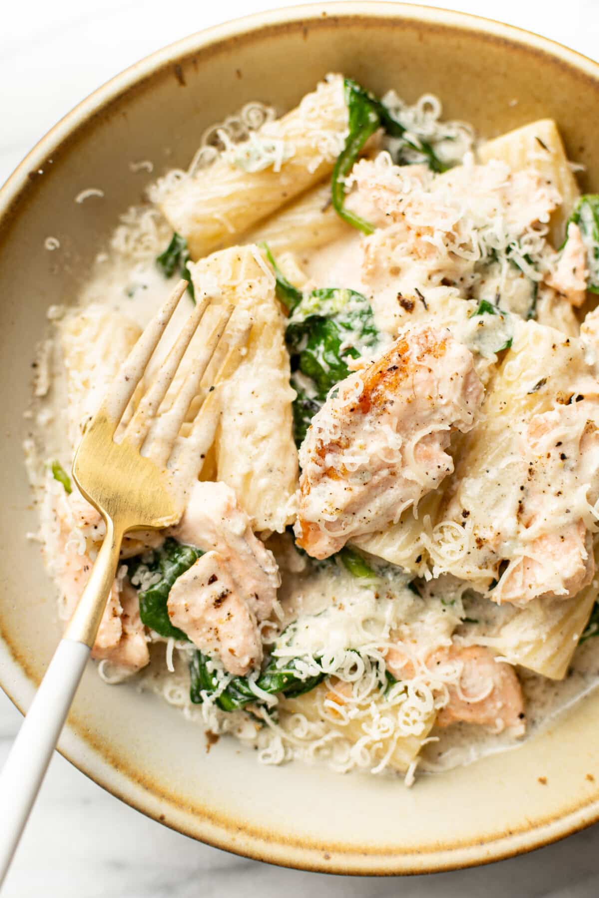 a bowl of lemon spinach salmon pasta with a fork