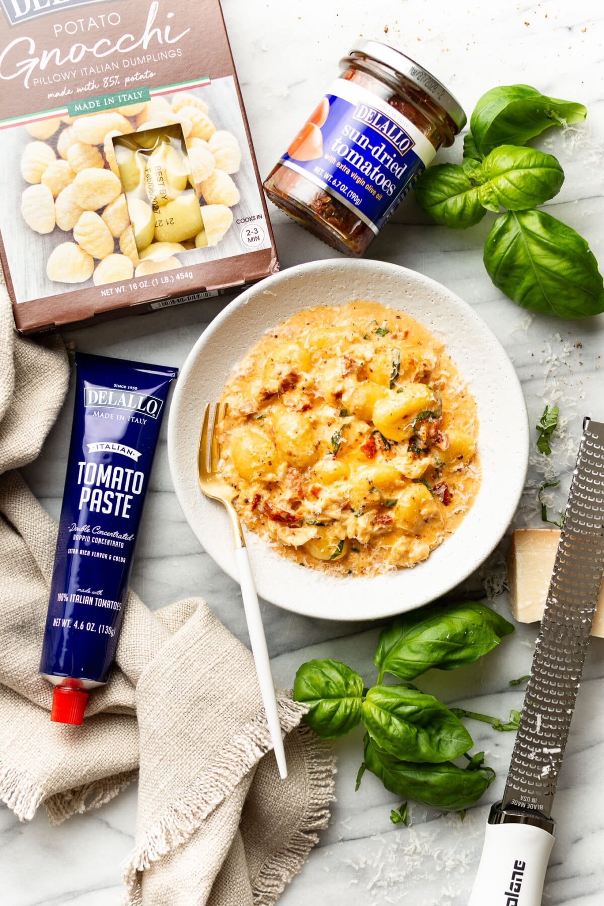 a bowl of marry me chicken gnocchi next to ingredients for it on a counter