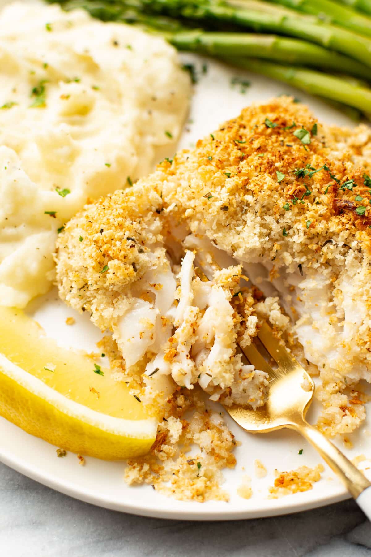 a plate with parmesan crusted cod, mashed potatoes, green beans, and a fork